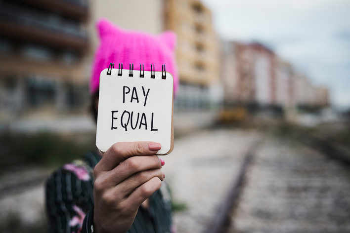 Frau hält Zettel hoch mit Pay Equal