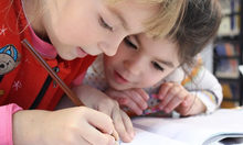 Grundschulkinderbetreuung - Zwei Kinder schreiben Lösungen auf.