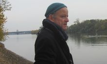 Mann mit Mütze und Kamera am Rhein stehend