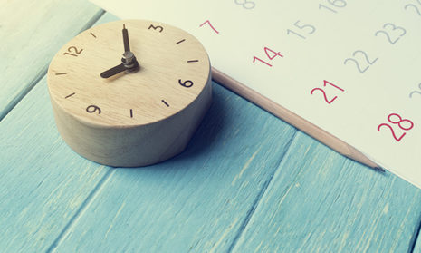 Uhr und Kalender liegen auf farbigen Hintergrund
