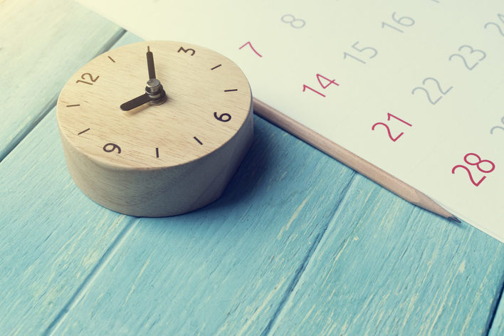 Uhr und Kalender liegen auf farbigen Hintergrund