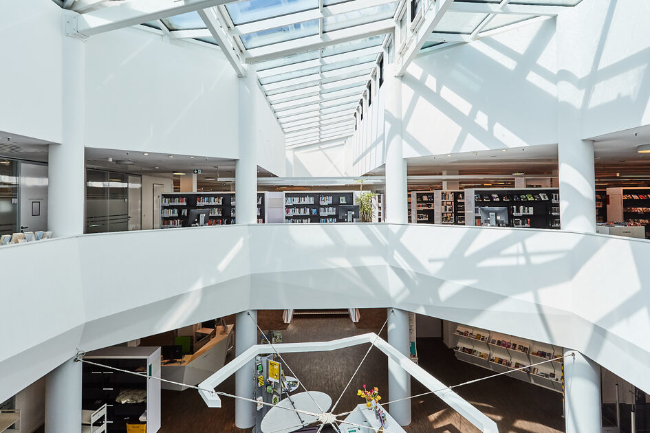 Blick in die Mauritius-Mediathek mit Bücherregalen auf mehreren Etagen und Glasdach.