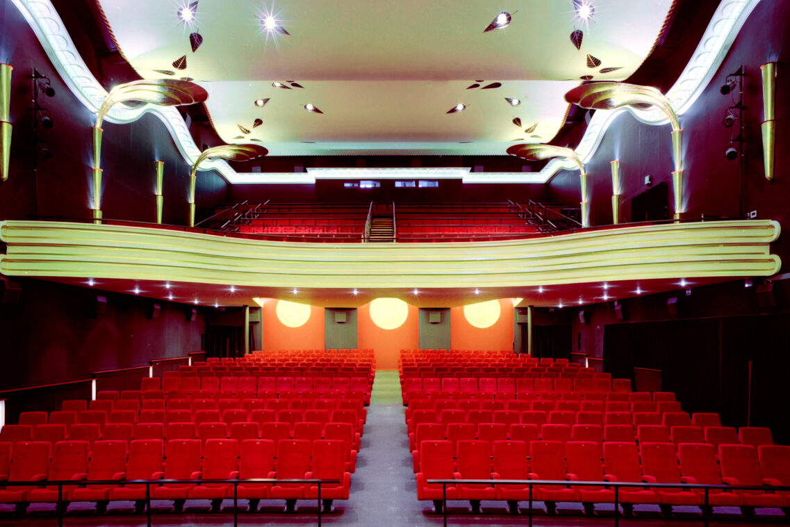 Salle de cinéma avec sièges rouges et lampes dorées