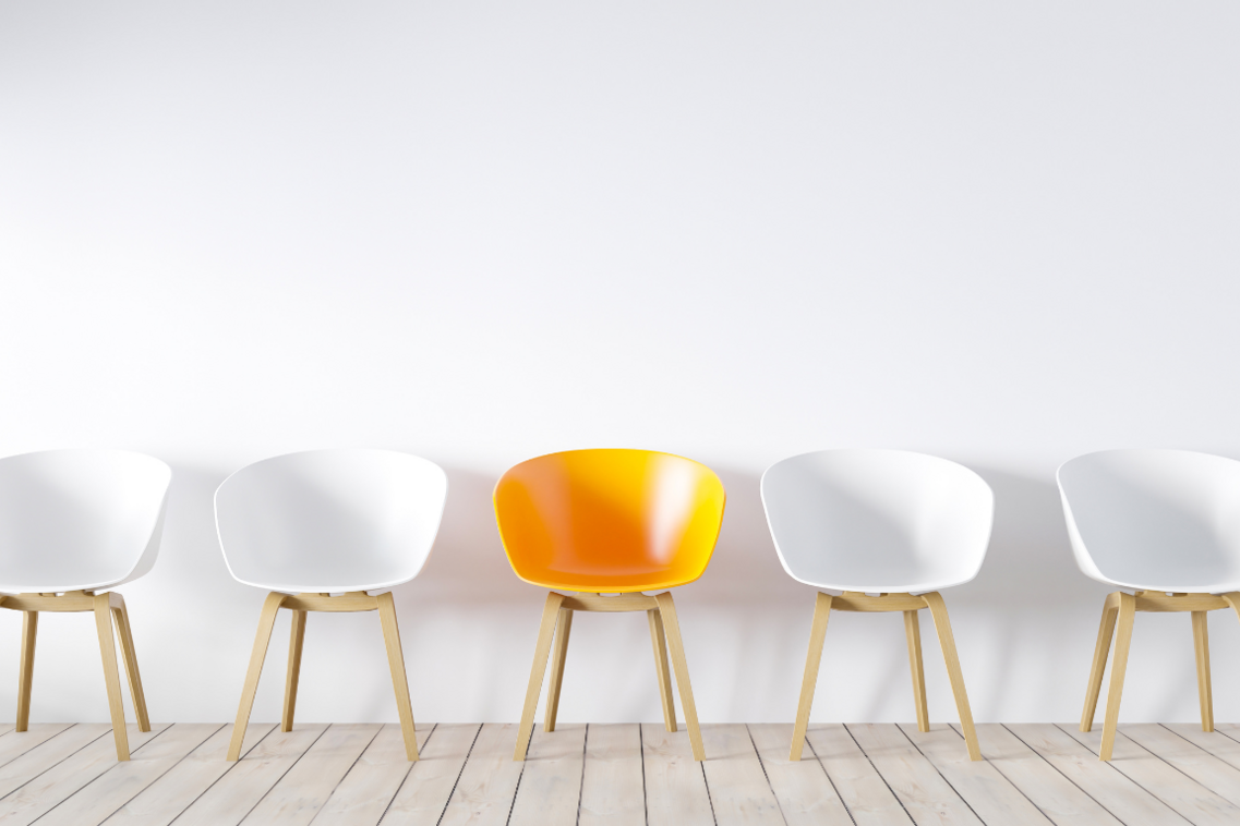 Quatre chaises blanches encadrent par deux une chaise orange au centre