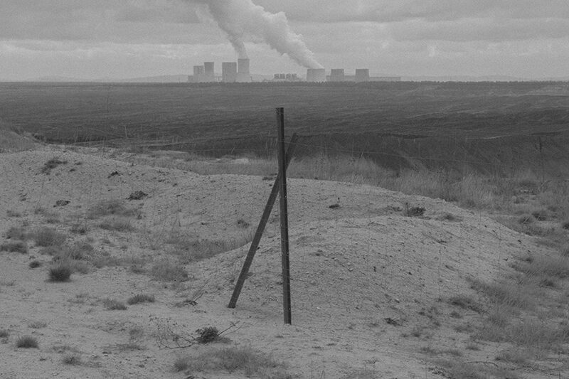 Пустинен пейзаж с небостъргачи и димящи комини на заден план