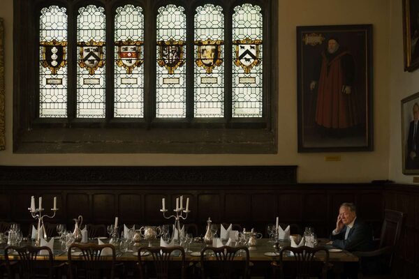 Ein Mann sitzt allein an einer großen gedeckten Tafel