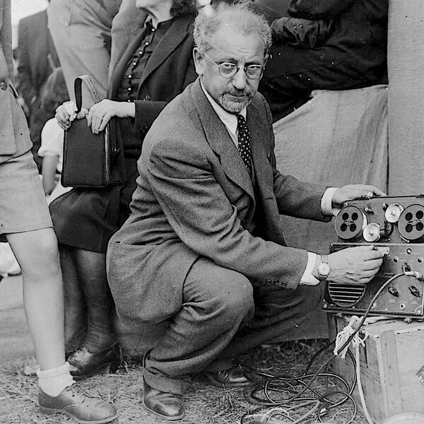 Ασπρόμαυρη φωτογραφία ενός άνδρα που σκύβει μπροστά από ένα μαγνητόφωνο