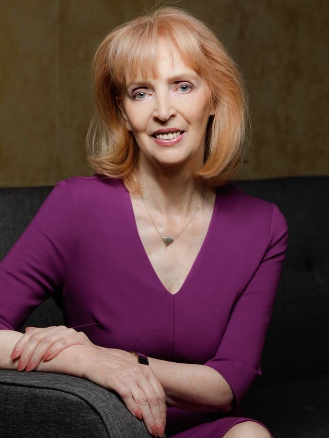 Porträtfoto einer sitzenden Frau im lila Kleid