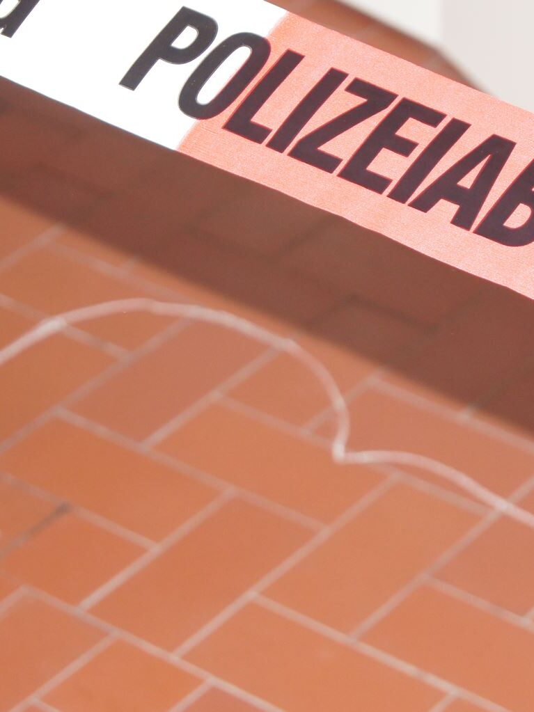 Ein Polizeiabsperrband über einen auf dem Boden mit Kreide gezeichneten Kopf