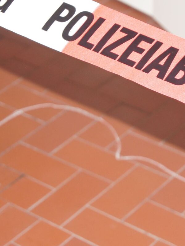 A police barrier tape over a head drawn on the ground with chalk