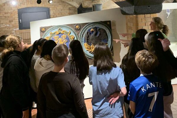 Gli alunni sono in piedi con l'insegnante davanti a un oggetto del museo