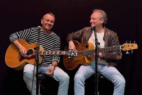 Two men with guitars on stools