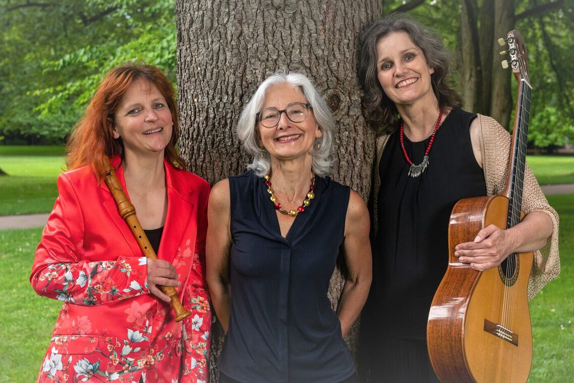 Сивистри се занимава с поезия. Три жени стоят до едно дърво и се усмихват на камерата. Жената вляво е облечена в червено и държи диктофон. Жената в средата е облечена в черно. Жената вдясно също е облечена в черно и държи китара.