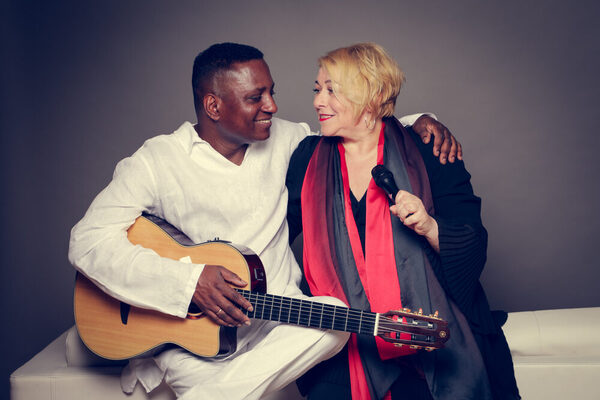links farbiger Mann mit Gitarre, rechts weiße Frau mit Mikrofon