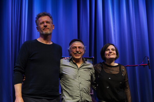 Gruppenfoto von dem Trio vor einem blauen Vorhang. Alle lachen erleichtert. Ganz links, Uwe Oberg, ist deutlich größer als die anderen beiden.