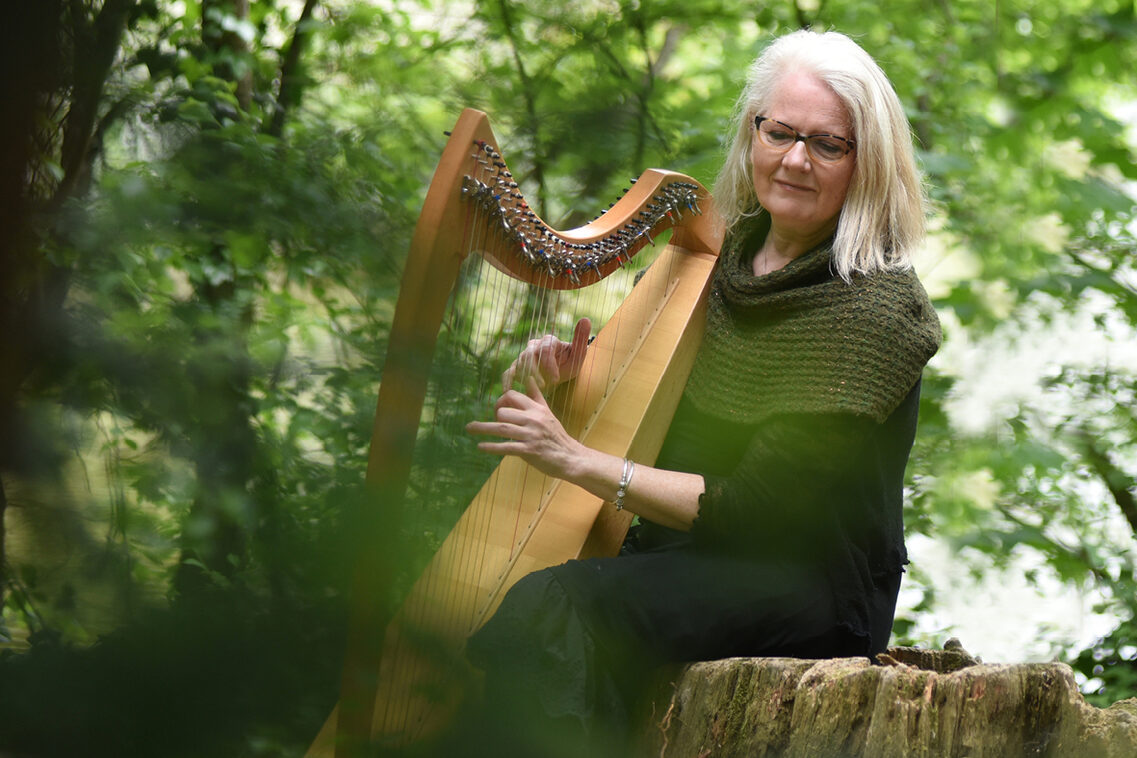 Жена седи в гората и свири на арфа. Тя е седнала на дънера на едно дърво и всичко изглежда много спокойно и отпуснато. Тя свири на арфа.