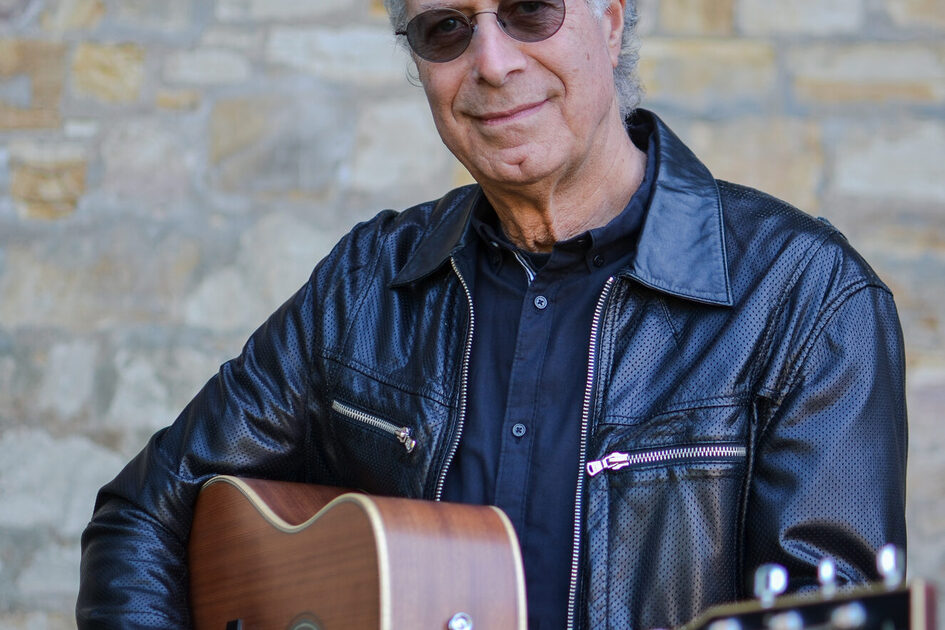 Helt Oncale elinde bir gitarla. Taş bir duvarın önünde durur ve kameraya bakar.