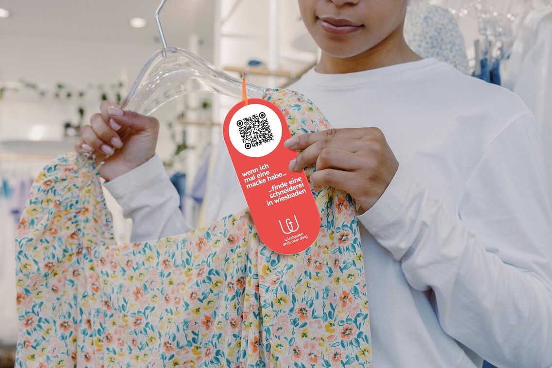 Frau mit Kleid auf Bügel und rotem Zettel