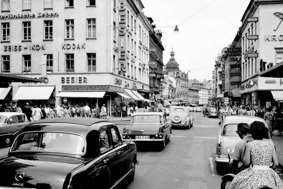 Ein Bild das den Autoverkehr 1962 in einer Straße zeigt.