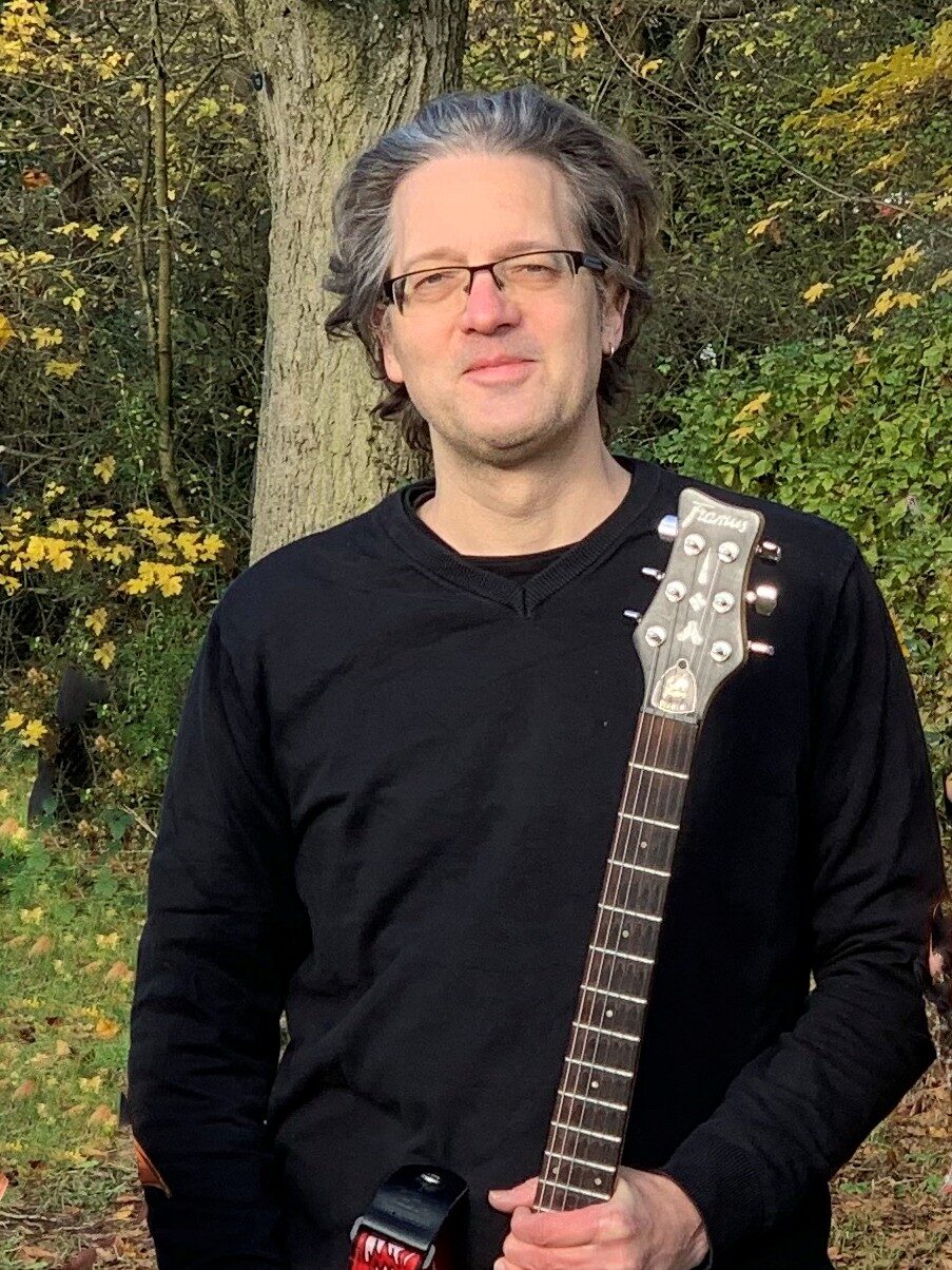 Man in the green holds electric guitar