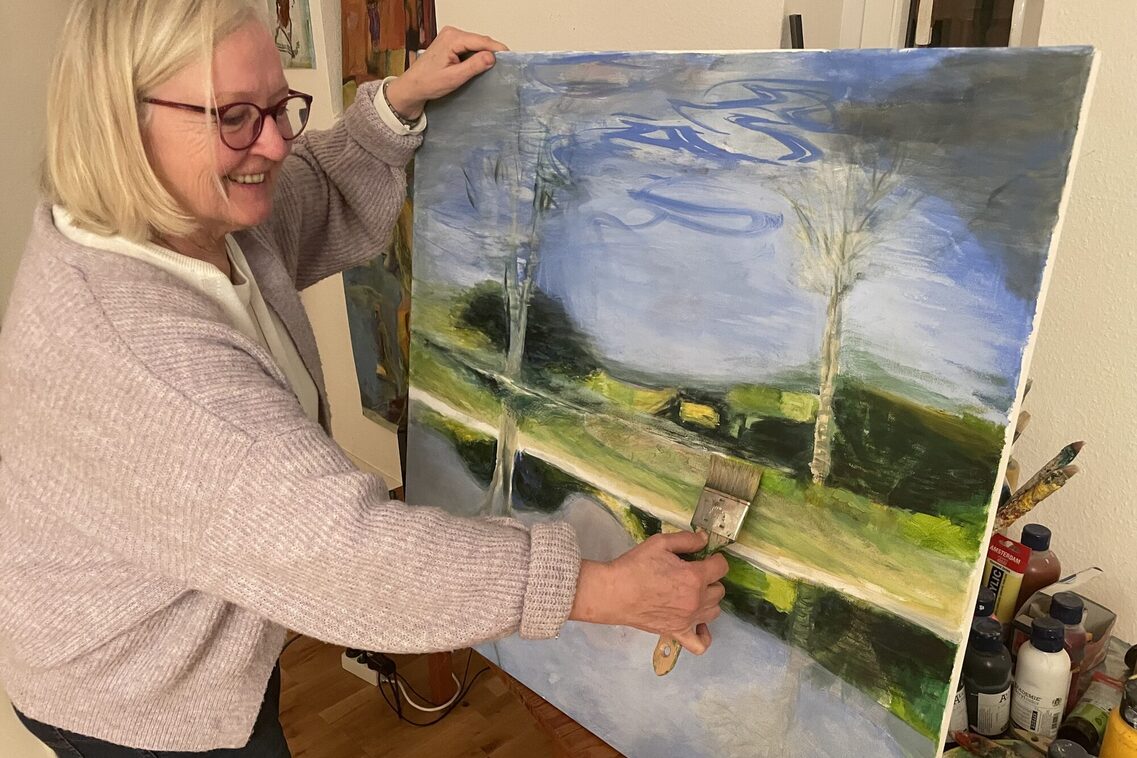 Künstlerin mit farbigem Landschafstbild und Pinsel