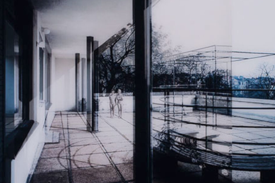 Eine Fotografie von Dirk Brömmel, das zwei unbekleidete Personen auf der Terrasse eines Hauses zeigt.