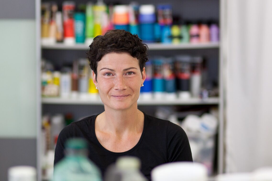 Künstlerin Christiane Mader, im Hintergrund Schrank mit Farben