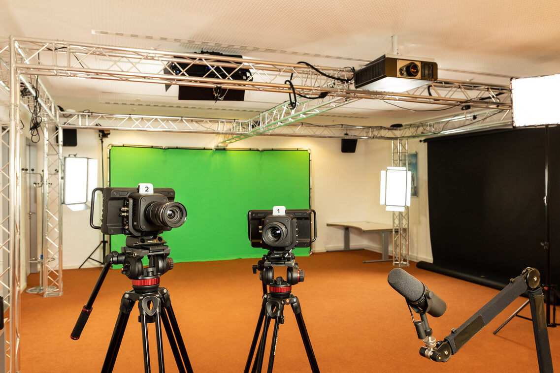 Raum mit Green-Screen, Kameras und einem Mikrophon auf Stativen