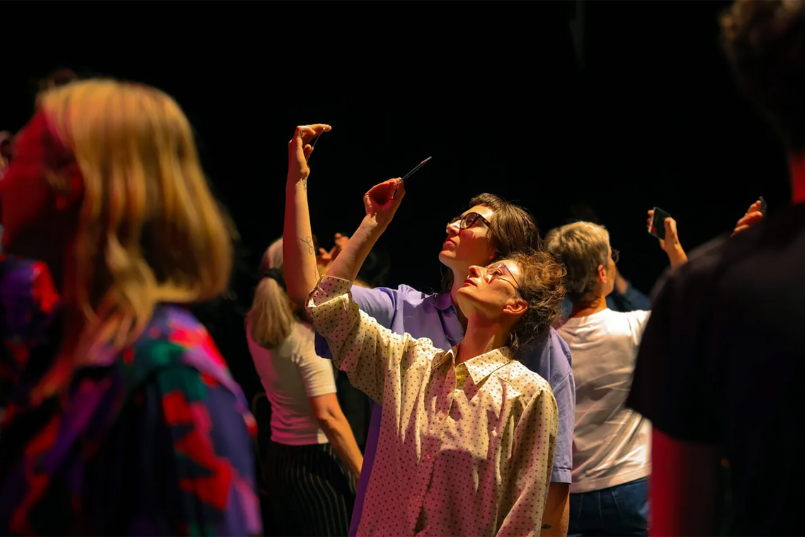 Frauen schauen nach oben auf ihr Smartphone.