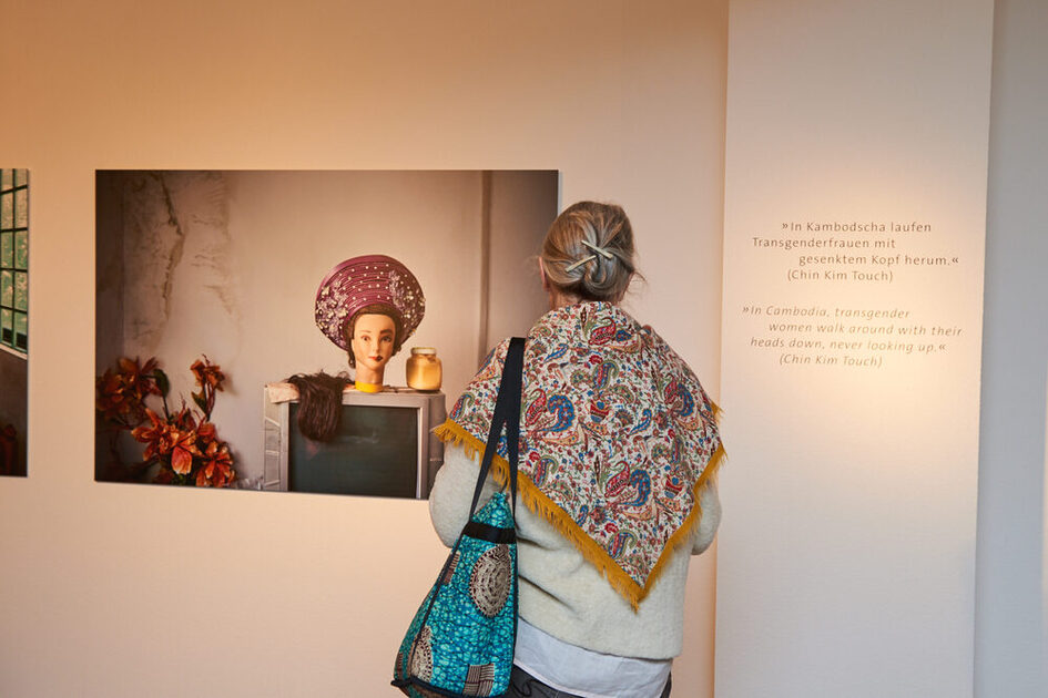 Frau mit Schal von hinten zu sehen. Sie blickt auf ein Bild