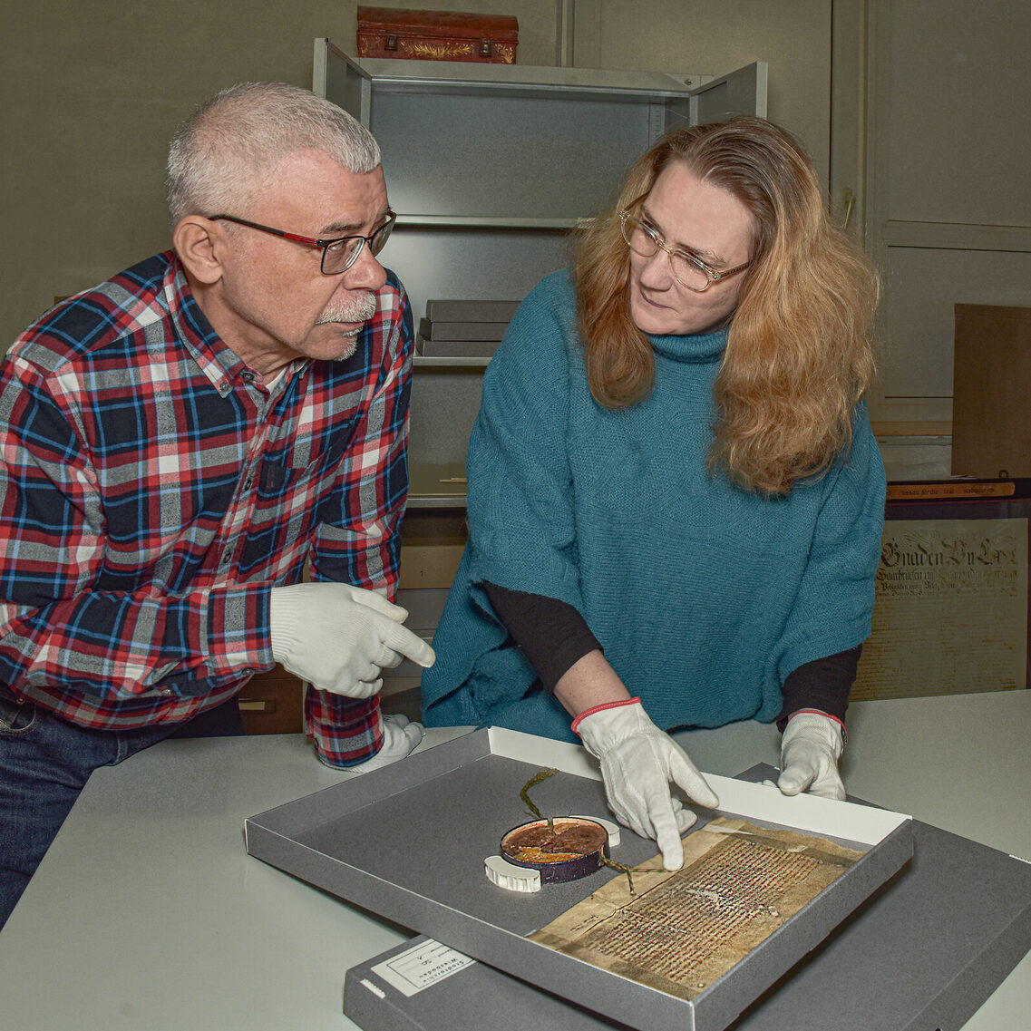 Zwei Mitarbeiter des Hauses recherchieren an der ältesten Urkunde