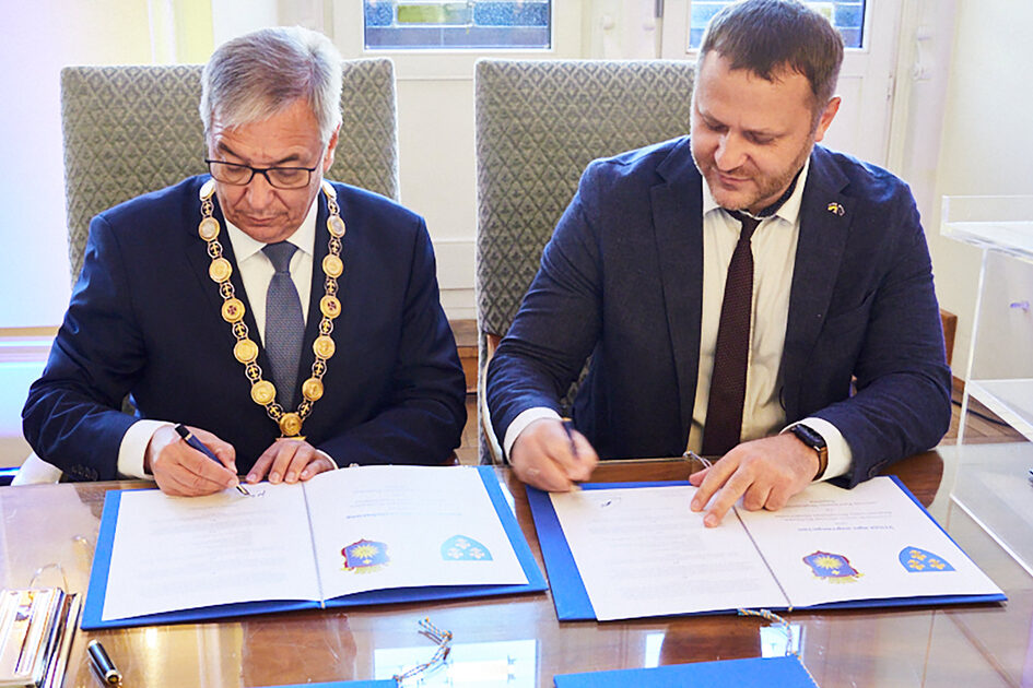 Zwei Männer in dunklen Anzügen unterschrieben Urkunden.