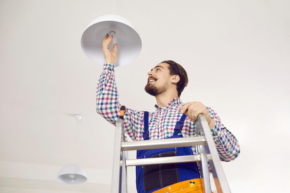 Electrician,Screwing,In,Light,Bulb,At,Home.,Happy,Man,In