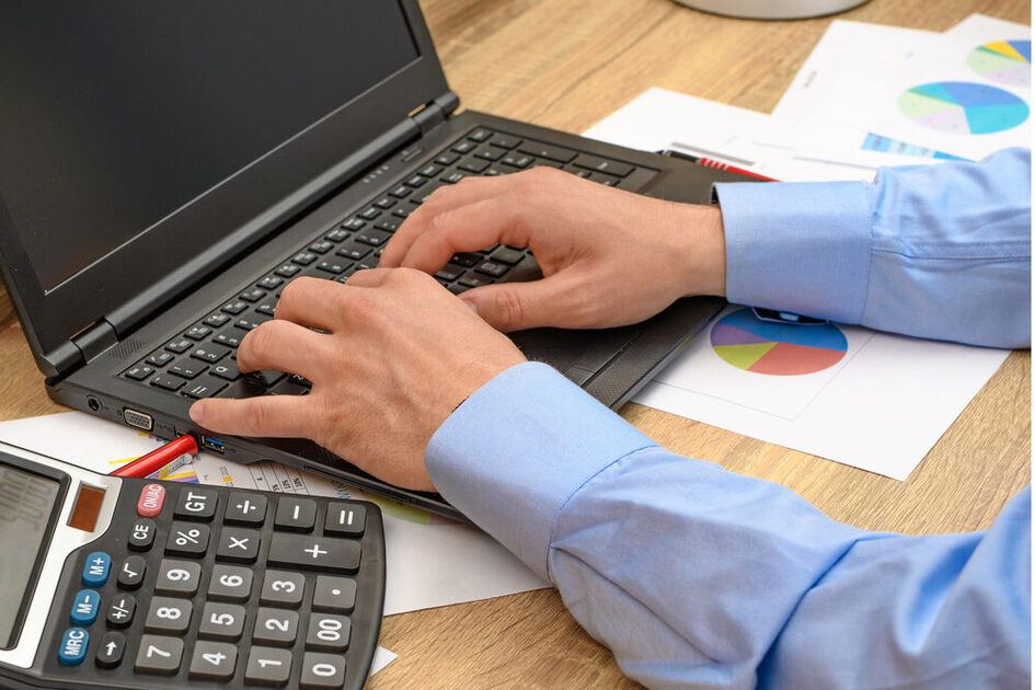 Mann tippt in einen Laptop