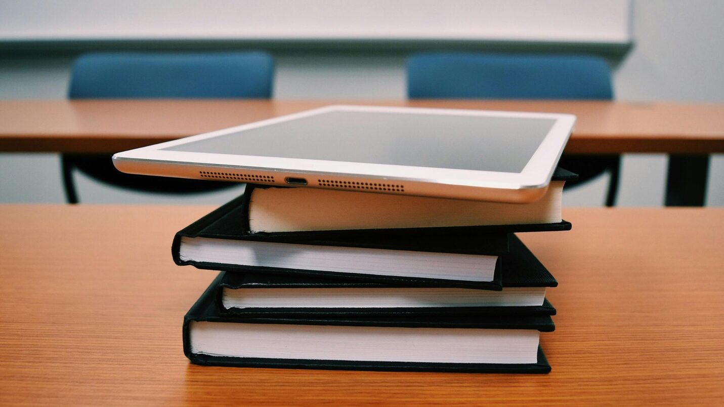 Ein Bücherstapel, auf dem oben ein Tablet aufliegt