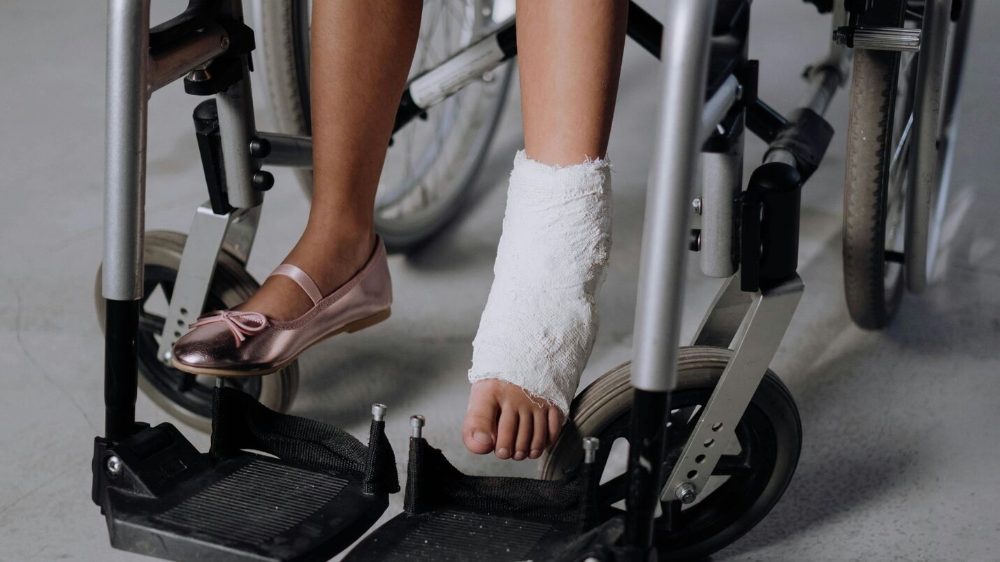 Ein Kind im Rollstuhl mit Fuß im Gips