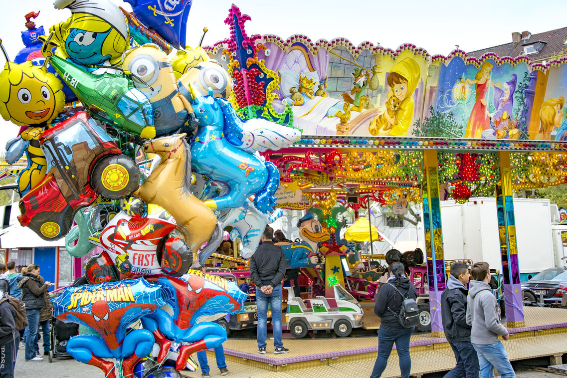Frühlingsfest: Zahlreiche Buden und Fahrgeschäfte auf einem Festplatz.