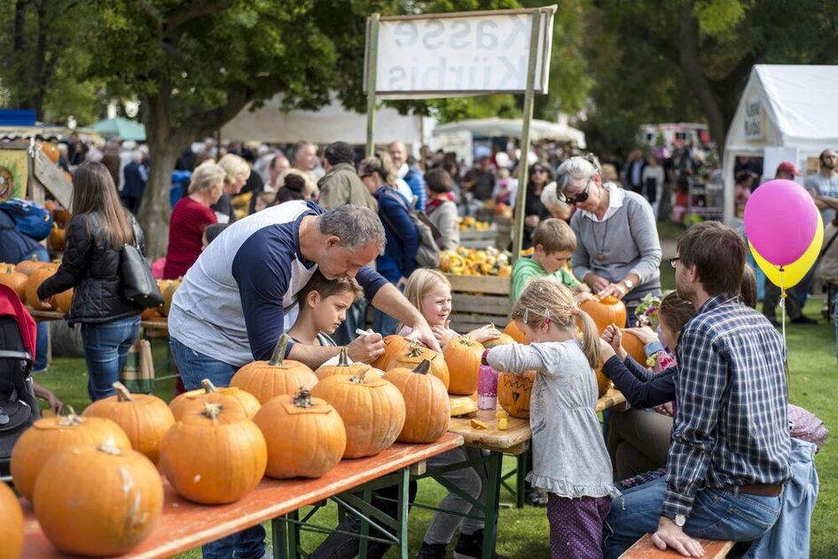Eltern malen mit Kindern Kürbisse an.