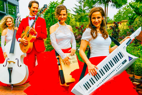 Drei Musikerinnen und ein Musiker in Rot und Weiß.