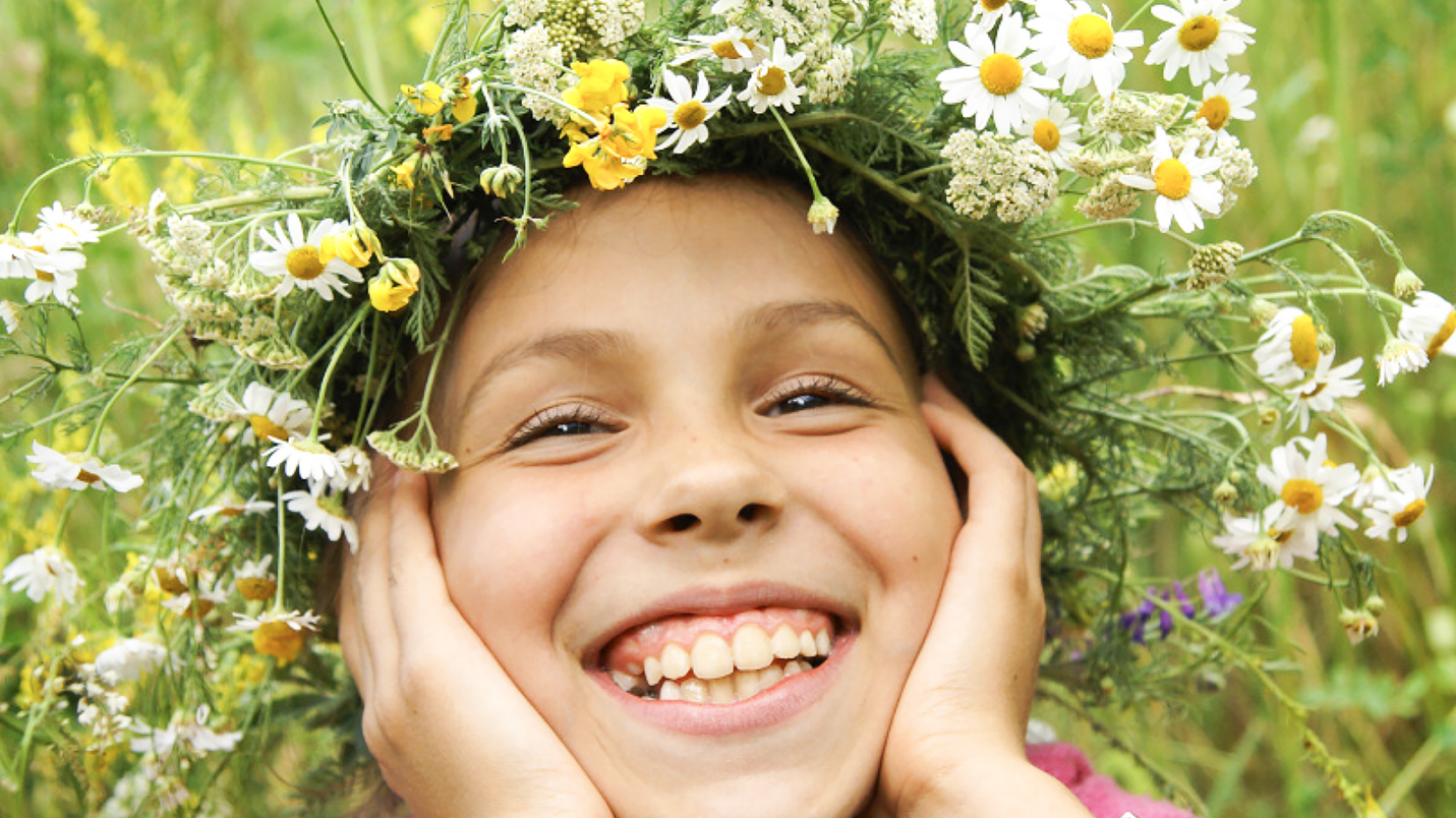 Ребенок с венком из цветов на летнем лугу