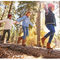 Kinder balancieren im herbstlichen Wald über Baumstamm