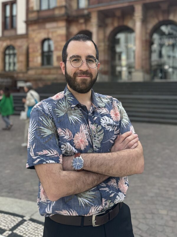 Mann mit buntem Hemd und Brille.