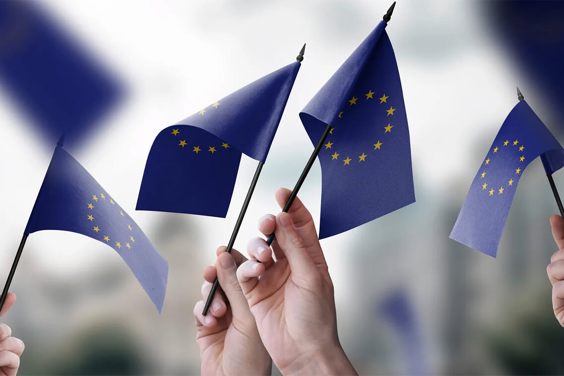 Küçük Avrupa bayraklarını sallayan eller.
