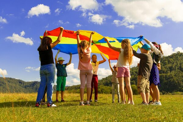 Viele Kinder, welche mit einem bunten Tuch spielen