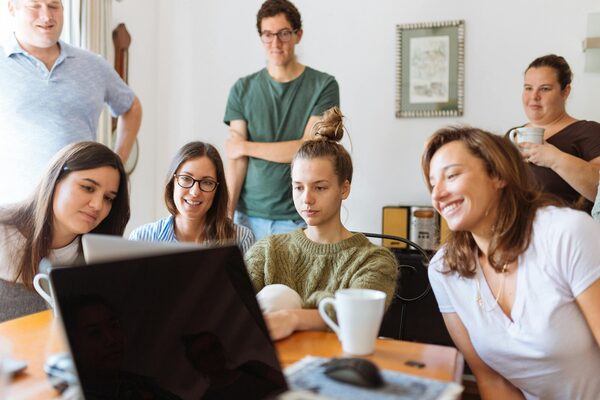 Sieben Menschen schauen gemeinsam in einen Bildschirm und Brainstormen