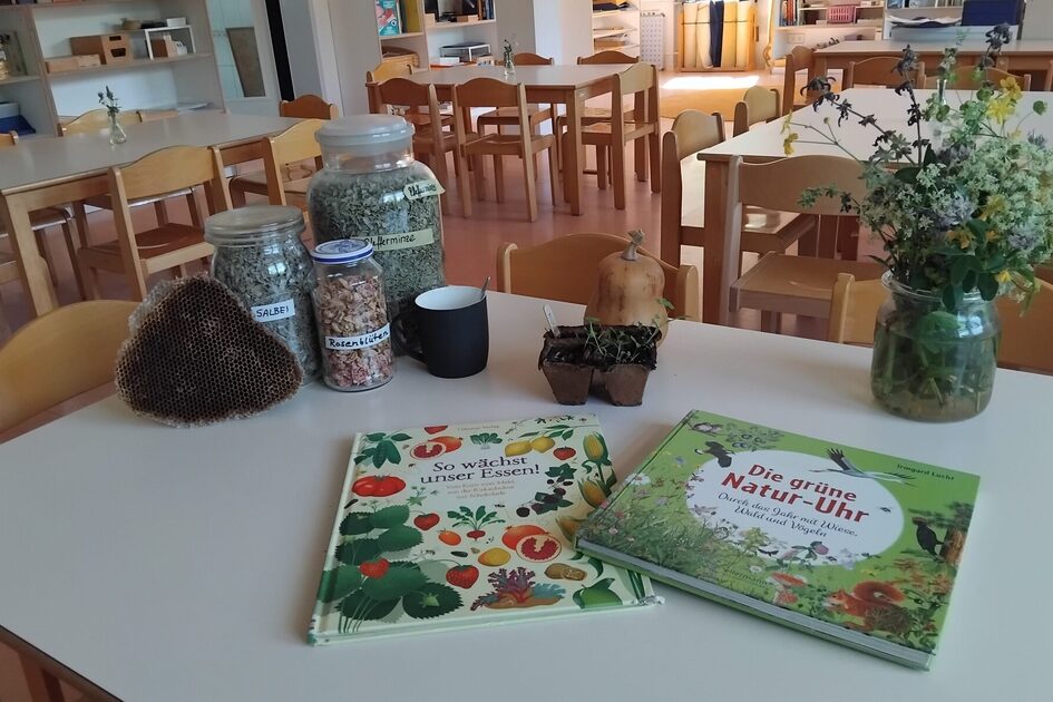 Der Tisch ist dekoriert mit Blumen, Gläser mit Samen und Bücher rund um das Thema Essen
