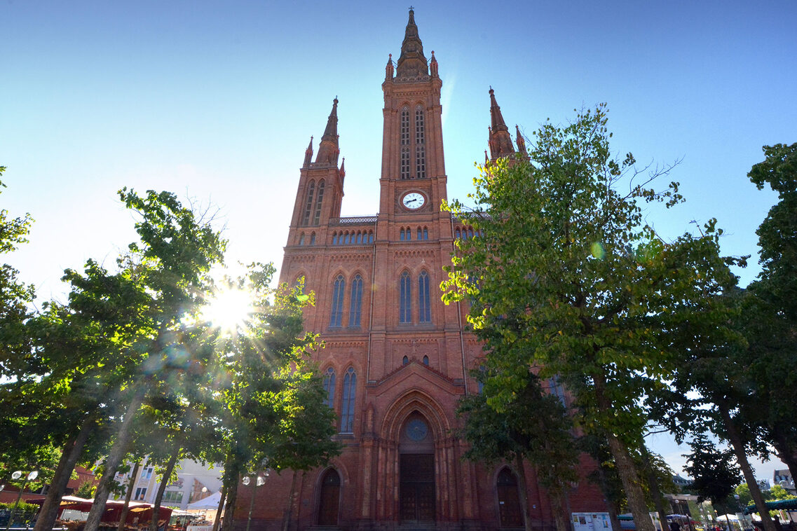 Backsteinkirche mit Bäumen und blauem Himmel