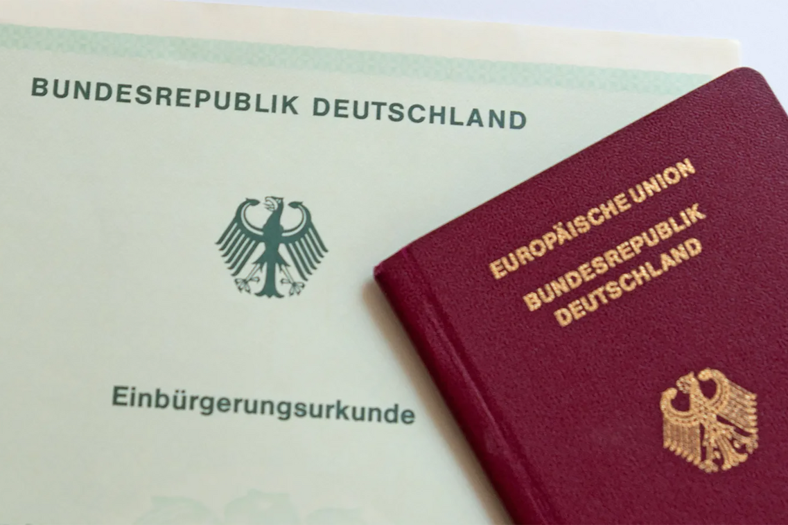 Ein Dokument mit der Aufschrift "bundesrepublik Deutschland - Einbürgerungsurkunde" und ein Deutscher Pass.