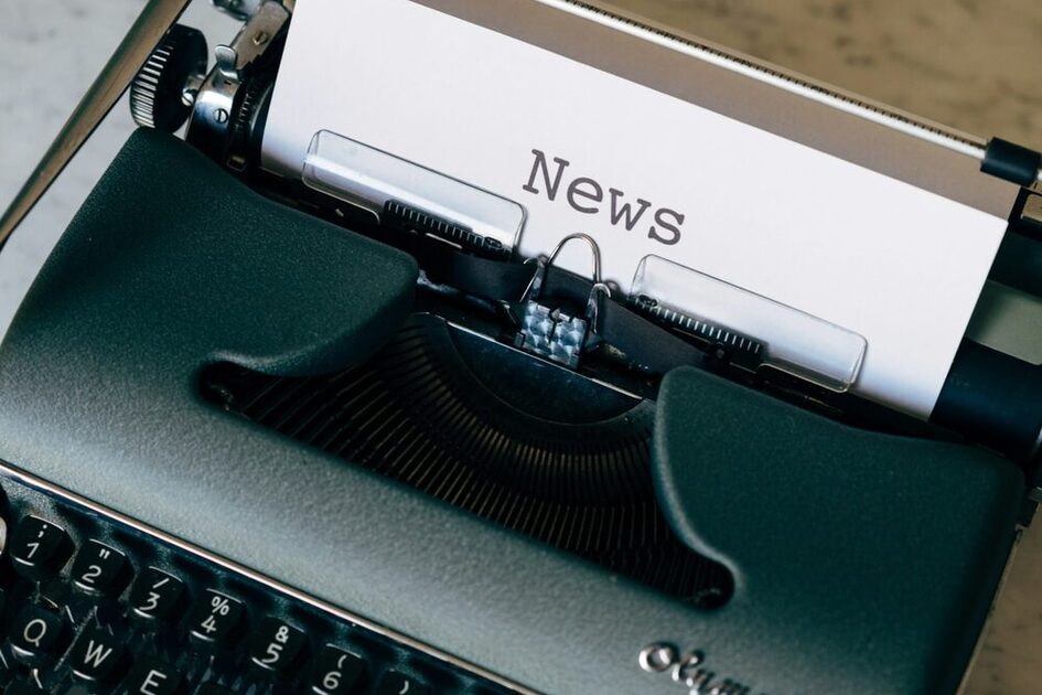 Grün-weiße Schreibmaschine auf braunem Holztisch.