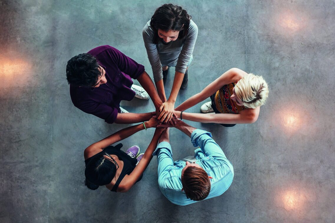 Five people put their hands over each other